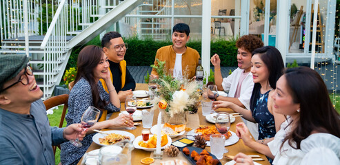 Group of diversity Asian millennial people friends enjoy outdoor garden dinner party eating food and drinking wine with talking together. Reunion friendship meeting celebration and night life concept.