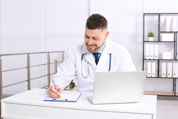 Fototapeta premium Pediatrician working on laptop at desk in office