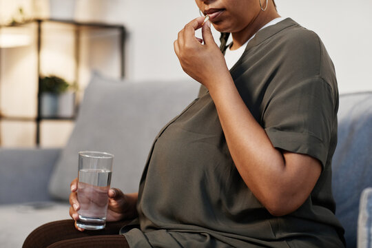 Side View Portrait Of Pregnant African-American Woman Taking Prenatal Vitamins At Home, Copy Space