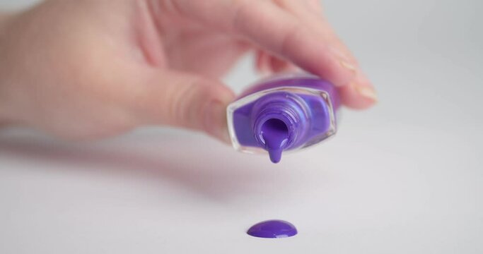 Woman spilling nail polish on light background, closeup