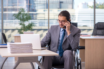 Young male employee in wheel-chair working in the office