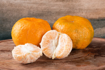 Ripe tangerine fruit with pieces on wooden background.