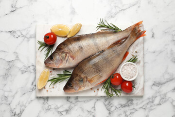 Fresh raw perches and ingredients on white marble table, top view. River fish