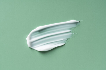 Green White cosmetic cream on green background.