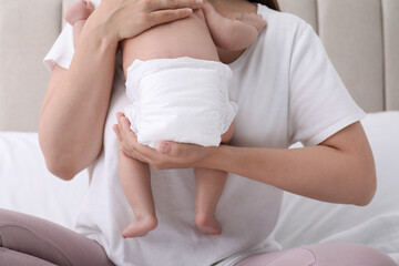 Mom holding her baby in diaper at home, closeup