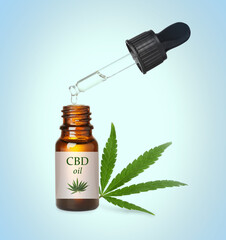 Bottle of cannabidiol tincture and hemp leaf on light blue background