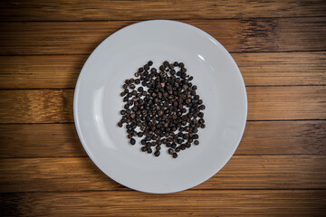 Black Pepper on white plate, wood background, ingredient seasoning herb vegetable