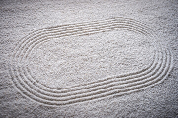 Fototapeta na wymiar Japanese Zen garden raked with a simple sports running track oval in textured white sand