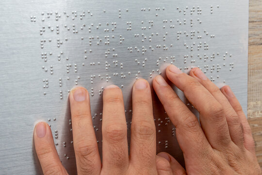 Close up of male hand reading braille text