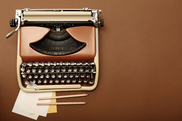 Vintage typewriter and stationery on brown background, flat lay. Space for text