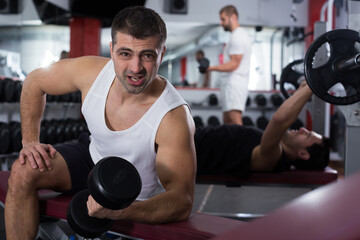 Portrait of athletic man exercising with dumbbells in gym