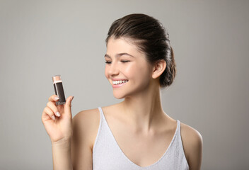 Beautiful girl with stick foundation on light grey background