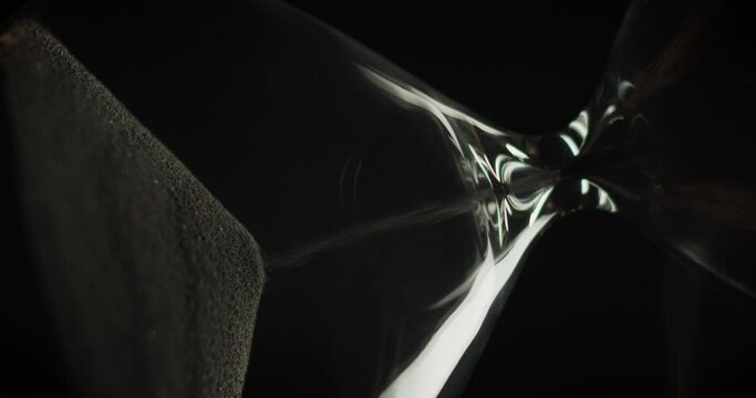 Macro shot of an hourglass slowly rotating while smoke wrapping it. Abstract running time concept. 
