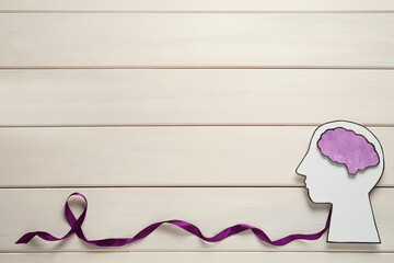 Human head cutout, brain and purple ribbon on white wooden background, flat lay with space for text. Epilepsy awareness