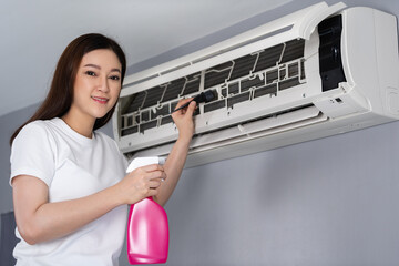 woman cleaning the air conditioner indoors at home