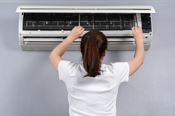 woman removing air filter of the air conditioner for cleaning at home
