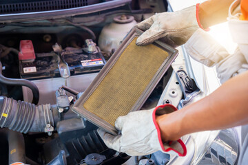 Auto mechanics holding air filter of car in the engine room, technician doing the checklist for repair car engine in the garage