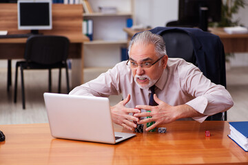 Old male employee in gambling concept at workplace