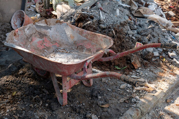 red wheelbarrow on a pile of sand for home renovation needs - obrazy, fototapety, plakaty