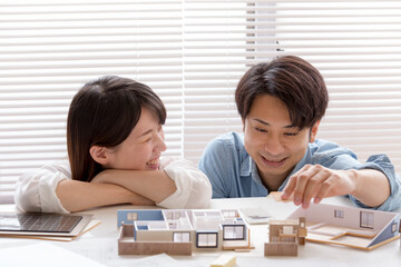 住宅模型を見ながら打ち合わせする施主、夫婦