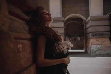 Curly girl in a black dress against the backdrop of the city