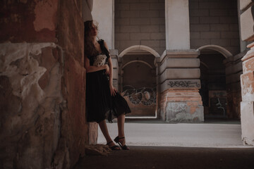Naklejka na ściany i meble Curly girl in a black dress against the backdrop of the city