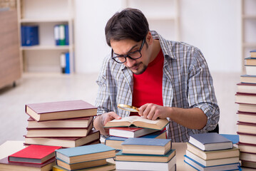 Young male student and too many books in the classroom