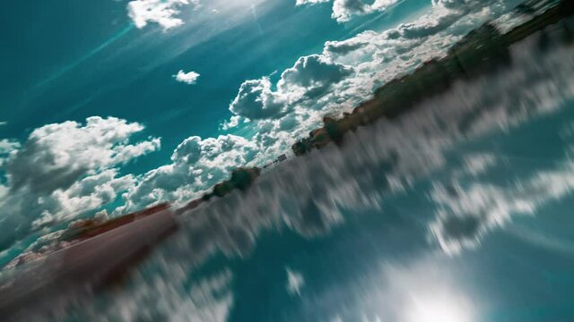 A dream flight over the mirrorlike surface. White clouds floating in the blue sky above and are reflected in the liquid mirror below. The camera is turning and circling imitating a rollercoaster ride