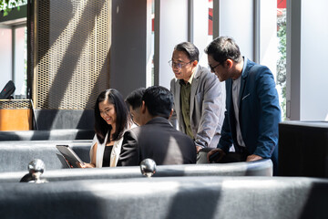 Group of Asian businesspeople wearing suit discussing and using computer in conference room. Diverse businesspeople working and sharing ideas concept on sofa in the office. business, people © amorn