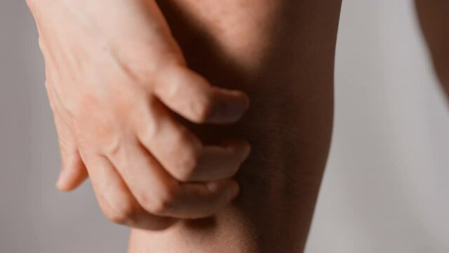 膝の裏を掻く男性　アトピー性皮膚炎