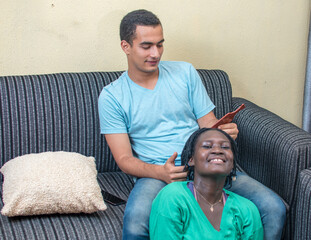 Smiling and lovely interracial couple of an African mother and a white man sitting happily together...