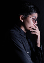 Studio portrait of a Thai Asian LGBT, woman wearing glasses is handsomed on a black backdrop.
