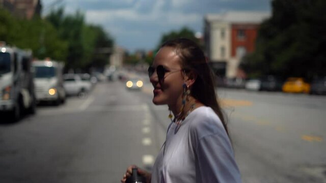 Happy young woman crosses the street in the center of a small town - isolated tracking view