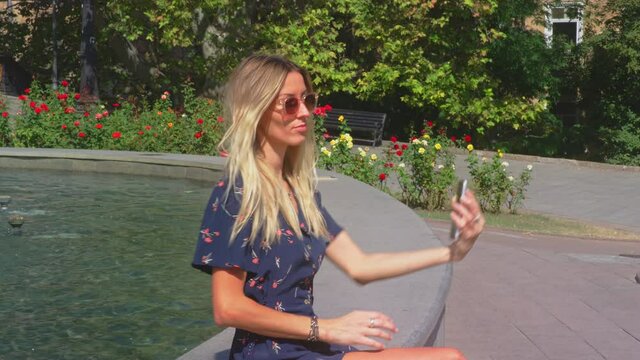Blonde Ukraine Woman Model Takes Selfie with Mobile Phone Sat on Fountain Edge