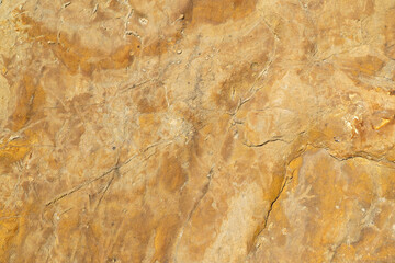 ‌Macro of uneven copper colored rock surface. Material for construction
