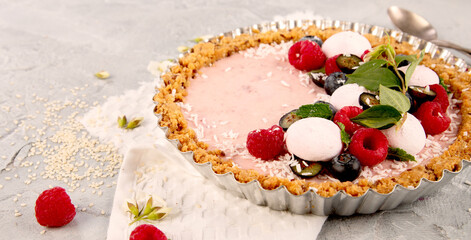 Strawberry vanila tart topped with berries on light gray background.