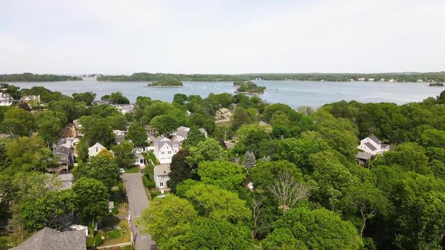 Aerial footage of coastal community at Hingham MA, showing trees in full summer foliage, drone jib down