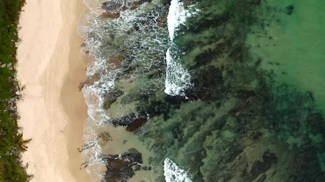 Top View Of A Couple Walking At The Sandy And Rocky Seashore Of Mooloolaba Beach In QLD, Australia. aerial