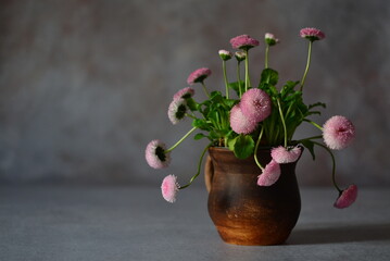 Pink daisies in a brown clay mug.