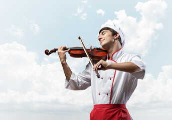 Young male chef playing violin