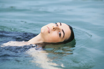 A dark-haired girl swims in the lake and takes a photo session