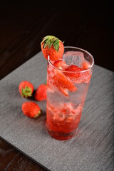 iced strawberry fruit cooler mocktail / kombucha in glass on bar counter dark night background cold halal drink menu