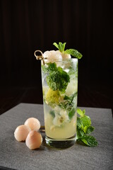 iced lychee longan mint fizz mocktail with mint leaf kombucha in glass on bar counter dark night...