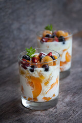 Two glasses of yogurt with apricots, strawberries and black currants