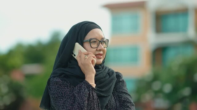 good looking Muslim women working off-site according to the slogan Work form home. She sits at work and talks on her cell phone. stay in private accommodation, 4k resolution.