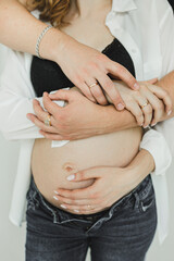 A husband hugs his pregnant wife's stomach. Naked pregnant belly. Light photography, love, trust and family values. Taking care of yourself and your neighbor.