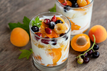Two glasses of yogurt with apricots, strawberries and black currants