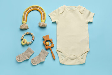 Set of baby clothes, socks and toys on color background