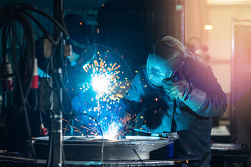 Epic industrial photo of worker. Welder team does work on metal, sparks and glare of light, blue...