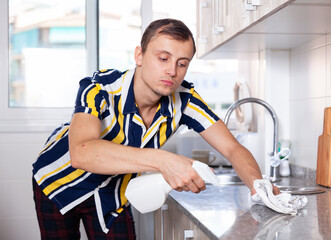 Smiling man is cleaning surface on the kitchen